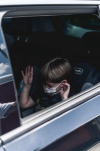 child sitting in the passenger seat of a vehicle with a mask on