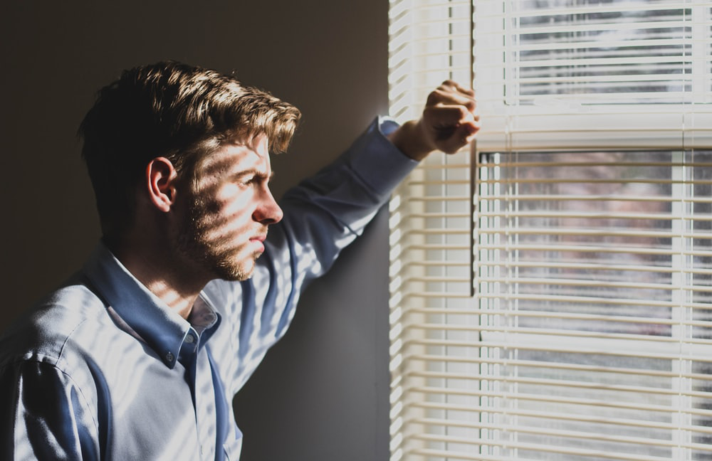 a depressed man looking out of his window
