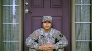 a Texas soldier sitting on the doorstep of her home