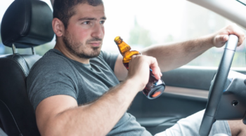 a man drinks a beer in his car