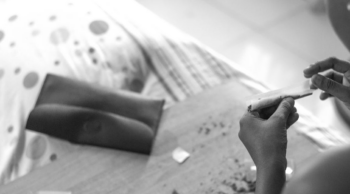 A black-and-white photo of a teenager rolling a joint