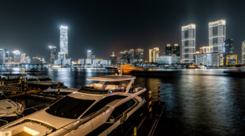 a boat sits at the marina at night with lit skyline in background